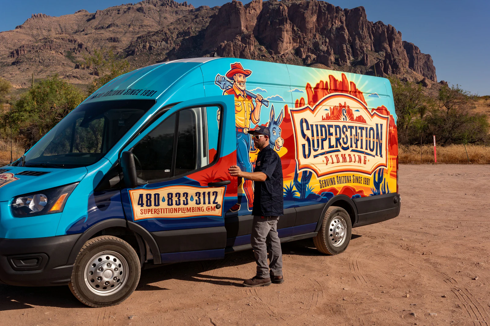 Superstition Plumbing technician with a wrapped service van in the Arizona desert